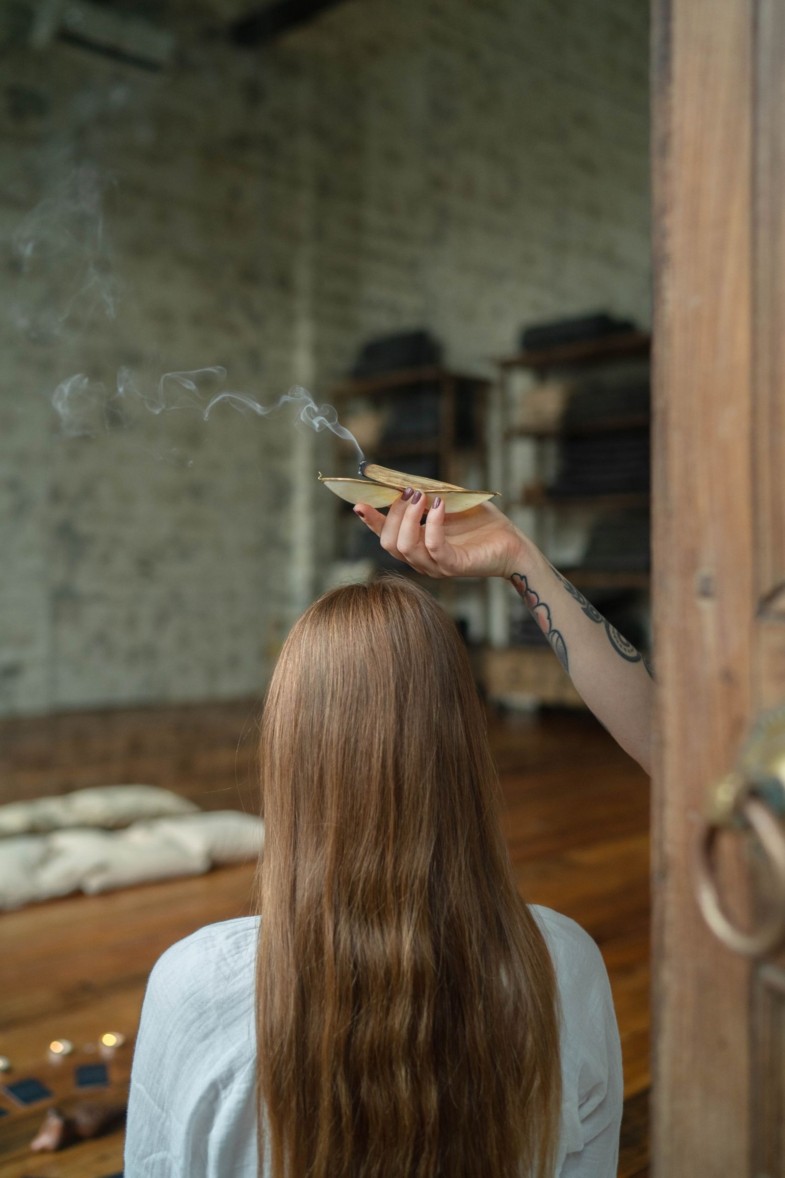 A person engaged in a spiritual practice using smudging rituals indoors.